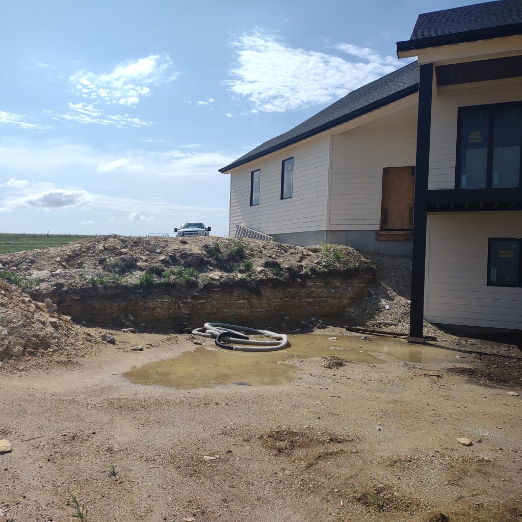 Workers install a large rock retaining wall on a new construction home.